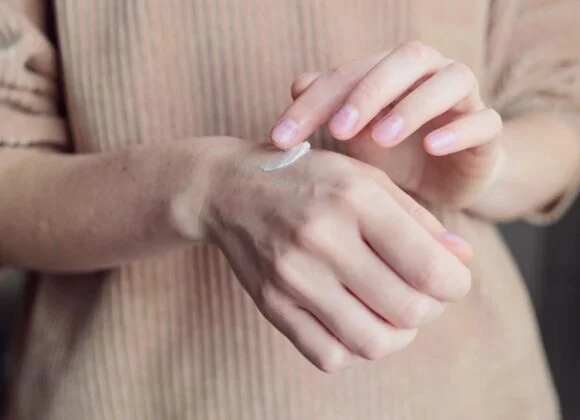 A person applies a dab of cream to the back of their hand.