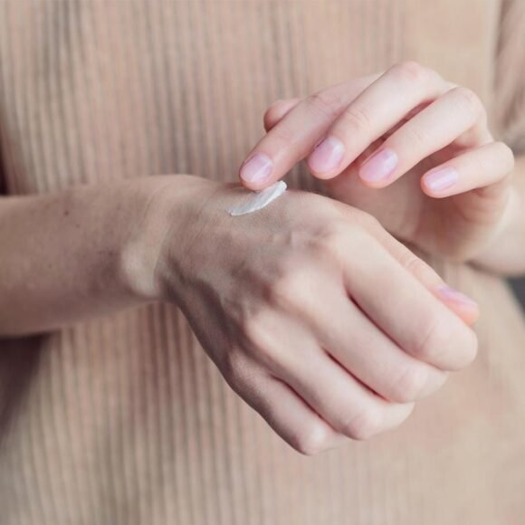 A person applies a dab of cream to the back of their hand.